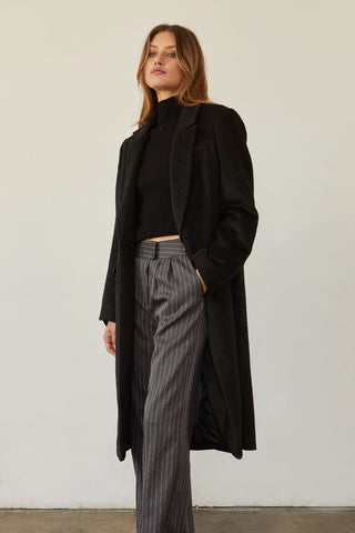 A model wearing a black brushed vegan wool coat.