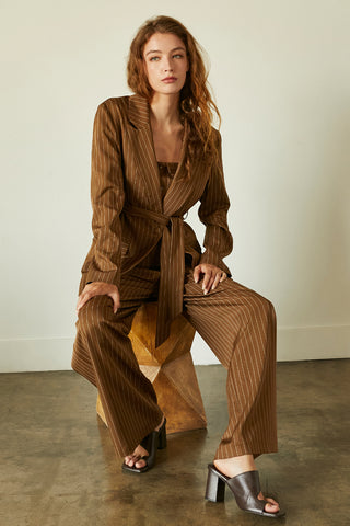 A model wearing a brown pinstriped blazer with waist belt.