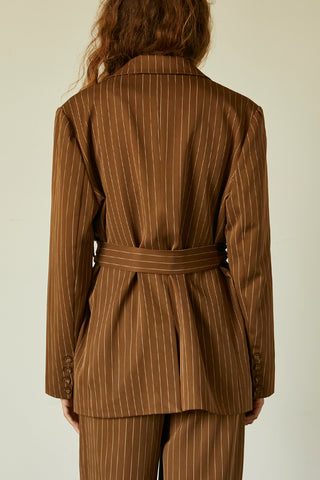 A model wearing a brown pinstriped blazer with waist belt.