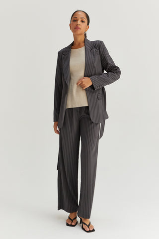A model wearing a grey pinstriped blazer with waist belt.