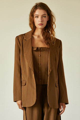 A model wearing a brown pinstriped blazer with waist belt.