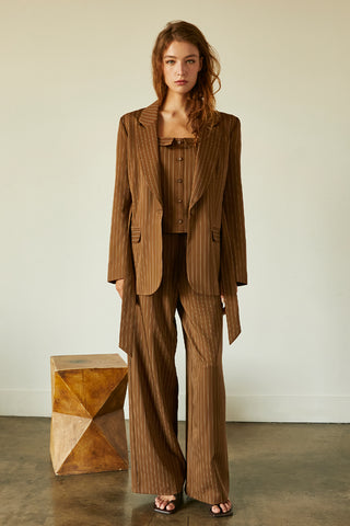A model wearing a brown pinstriped blazer with waist belt.