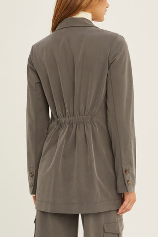 A woman wearing a charcoal Tencel utility blazer with matching pants.