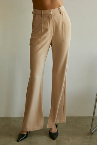 A model wearing a tan wide-leg trousers with slits at inseam hem.