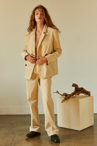 A woman wearing a beige corduroy trousers with matching corduroy blazer.