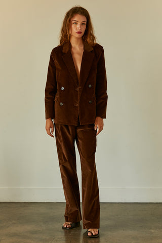 A woman wearing a chocolate corduroy trousers with matching corduroy blazer.