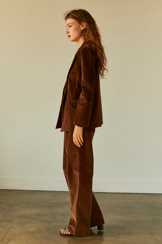 A woman wearing a chocolate corduroy trousers with matching corduroy blazer.