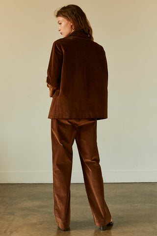 A woman wearing a chocolate corduroy trousers with matching corduroy blazer.