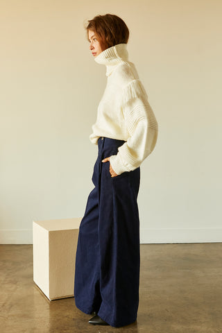 A model wearing a navy corduroy pants.