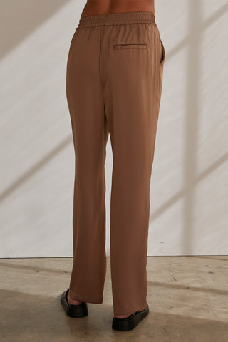 A model wearing a taupe satin elastic waist pants.