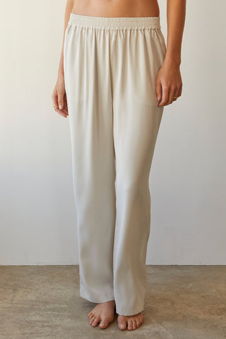 A model wearing a cream satin elastic waist pants.