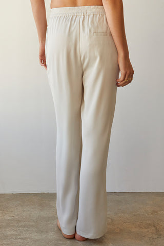 A model wearing a cream satin elastic waist pants.