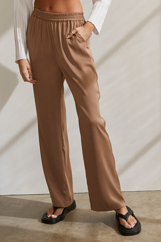 A model wearing a taupe satin elastic waist pants.