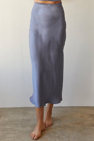 A model wearing a slate blue satin maxi skirt.