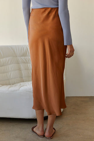 A model wearing a brown satin maxi skirt.