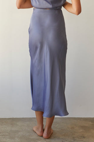 A model wearing a slate blue satin maxi skirt.