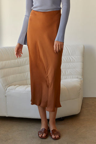 A model wearing a brown satin maxi skirt.