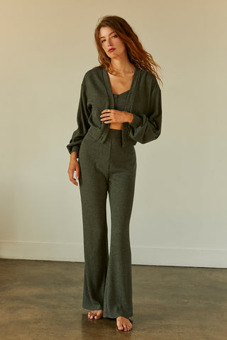 A woman wearing an olive stretchy ribbed 3-piece set comes in cropped tank, cardigan and pants.