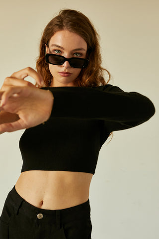 A woman wearing a black one shoulder long sleeve cropped top.