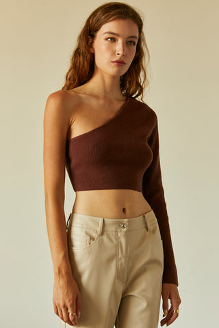 A woman wearing a chocolate one shoulder long sleeve cropped top.