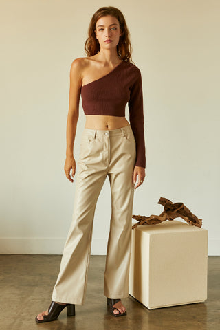 A woman wearing a chocolate one shoulder long sleeve cropped top.