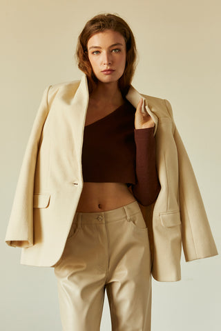 A woman wearing a chocolate one shoulder long sleeve cropped top.