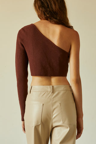 A woman wearing a chocolate one shoulder long sleeve cropped top.
