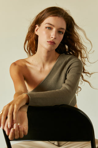 A woman wearing a moss one shoulder long sleeve cropped top.