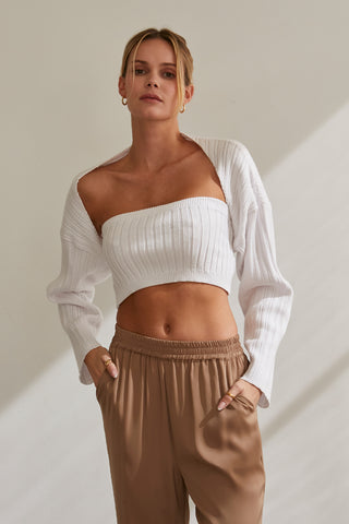 A model wearing a white stretchy knit bolero set.