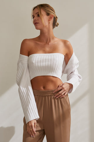 A model wearing a white stretchy knit bolero set.