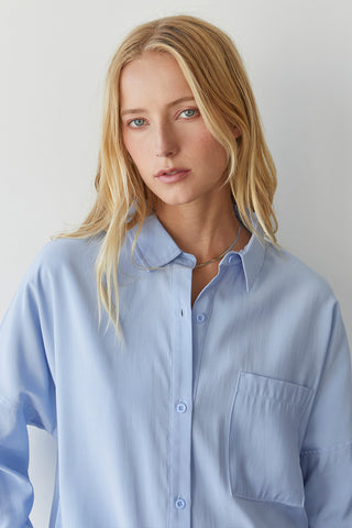 A model wearing a blue button up shirt.