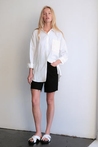 A model wearing a white button up shirt.