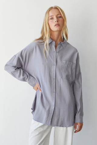 A model wearing a grey button up shirt.