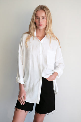 A model wearing a white button up shirt.