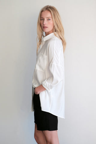 A model wearing a white button up shirt.