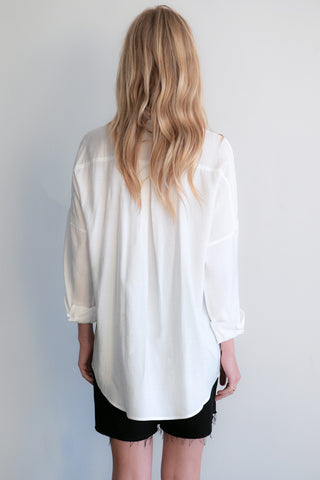 A model wearing a white button up shirt.