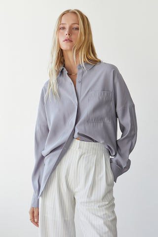 A model wearing a grey button up shirt.