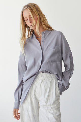 A model wearing a grey button up shirt.