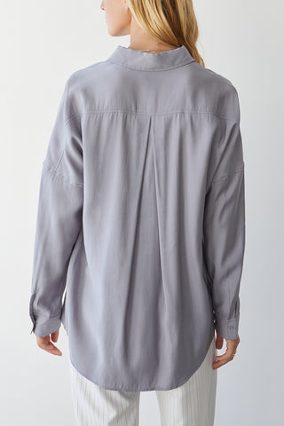 A model wearing a grey button up shirt.
