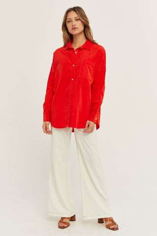 A woman wearing a red corduroy oversized shirt.