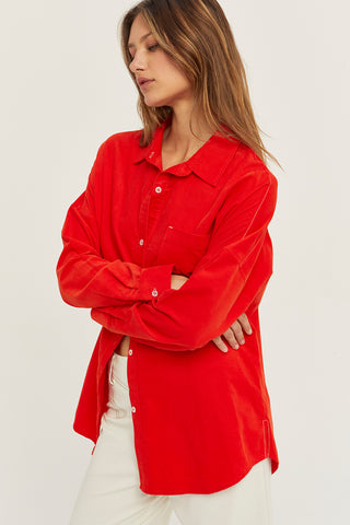 A woman wearing a red corduroy oversized shirt.