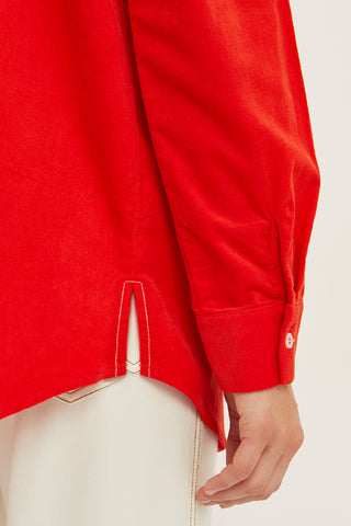 A woman wearing a red corduroy oversized shirt.