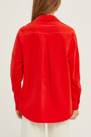 A woman wearing a red corduroy oversized shirt.