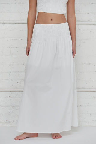 A woman wearing an ivory all-over smoked tube top and maxi skirt two piece set.