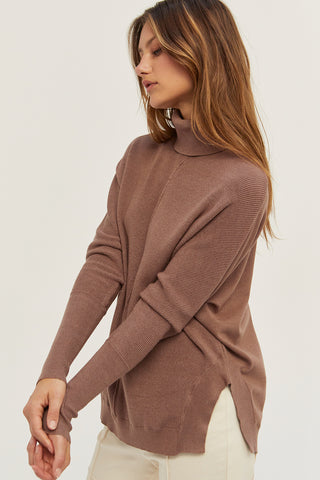 A model wearing a mocha dolman sleeve sweater.