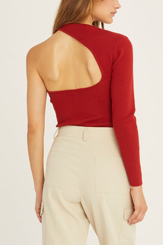 A woman wearing a brick one shoulder cut out sweater top.