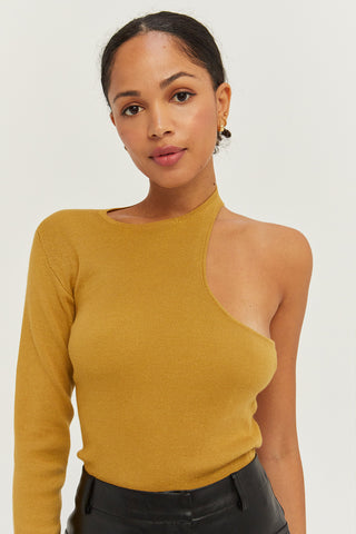 A woman wearing a marigold one shoulder cut out sweater top.
