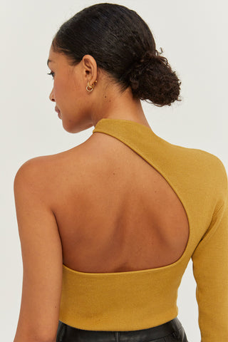 A woman wearing a marigold one shoulder cut out sweater top.