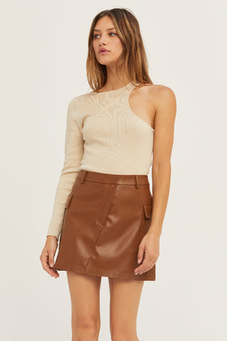 A woman wearing a bone one shoulder cut out sweater top.