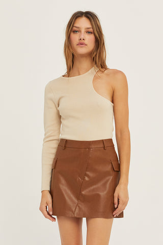 A woman wearing a bone one shoulder cut out sweater top.